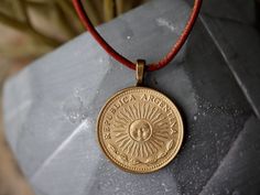 "Genuine Argentina coin on an 18\" leather cord; secures with lobster claw clasp. Features image of the Argentinian sun.   Since we use genuine foreign coins, necklaces may vary slightly from the photo due to unique wear and aging, but it will still be a close match. Whether this purchase is to help you connect to your roots, keep a precious dream or memory alive, or to remind you of a loved one we are glad to be a part of your journey! Find us on Facebook and Instagram @lostcoinjewelryco Orders are shipped in 1-3 business days." Waxed Cord Jewelry With Round Pendant As Gift, Waxed Cord Jewelry With Round Pendant For Gift, Gold Waxed Cord Jewelry For Gifts, Waxed Cord Round Pendant Necklace For Gift, Nickel-free Waxed Cord Necklace - Ideal Gift, Nickel-free Waxed Cord Necklace For Gifts, Vintage Waxed Cord Jewelry For Gifts, Spanish Jewelry, Sun Jewelry