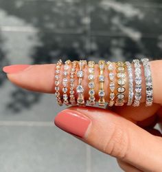 a woman's hand holding several different types of bracelets on her left wrist