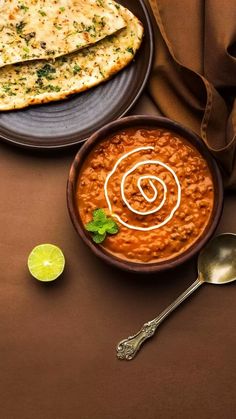 a bowl of beans and tortilla bread on a brown table with a spoon