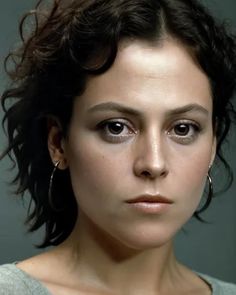 a close up of a person with dark hair and eyeliners, wearing large hoop earrings