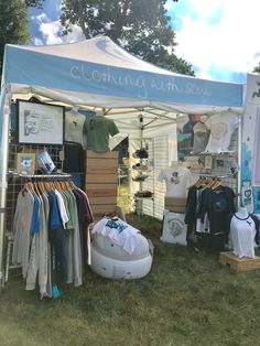 a tent with clothes on display in the grass