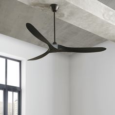 a ceiling fan is hanging from the ceiling in a room with white walls and windows