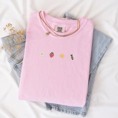 Welcome the sunny days with our Sunkissed Strawberry and Bee Embroidered T-Shirt! Made from 100% cotton Soft Comfort Colors, this shirt is both stylish and comfortable, perfect for your summer adventures.Features:Material: 100% cotton Soft Comfort ColorsSizes: S, M, L, XL, 2XL (refer to size chart in images)Colors Available: Banana, Bay, Blossom, Chalky Mint, Chambray, Ivory, Orchid, Peachy, Violet (Note: Colors may vary slightly due to monitor settings)Design: Summer-inspired embroidery featuring a daisy, strawberry, sun, and bee on the center chestCare Instructions: Machine wash cold, tumble dry lowThis Sunlissed Strawberry and Bee Embroidered T-Shirt is a delightful addition to your wardrobe, bringing a touch of sunshine wherever you go. Perfect for picnics, beach days, or casual outing Pink T-shirt For Everyday Summer Wear, Summer Floral Embroidery Relaxed Fit T-shirt, Summer Crew Neck T-shirt With Floral Embroidery, Summer Floral Embroidered Crew Neck T-shirt, Casual Summer T-shirt With Embroidered Graphics, Summer Embroidered Graphic Tee, Summer Cotton Tops With Strawberry Print, Summer Floral Embroidery T-shirt In Relaxed Fit, Spring Embroidered Top For Everyday Wear