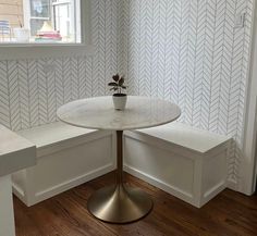 a white table with a potted plant on it in front of a wallpapered room