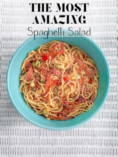 a blue bowl filled with spaghetti and tomato sauce on top of a white table cloth