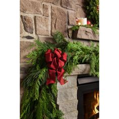 a fireplace decorated with evergreen and red bows