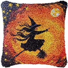 a decorative pillow with a witch flying through the night sky on an orange and yellow background