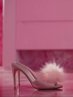 a pair of pink high heeled shoes with a white fur pom - pom