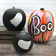 three painted pumpkins sitting on top of a wooden bench with ghost faces and boo written on them