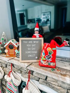 an elf sitting on top of a mantle holding a sign