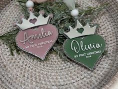 two personalized christmas ornaments in the shape of hearts and crowns on a wicker basket