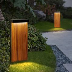 two wooden lights in the grass near some bushes