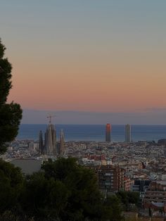 the city is lit up at sunset with tall buildings in the background and water beyond