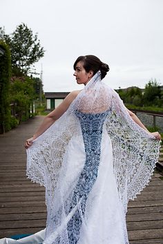 a woman in a wedding dress is standing on a boardwalk