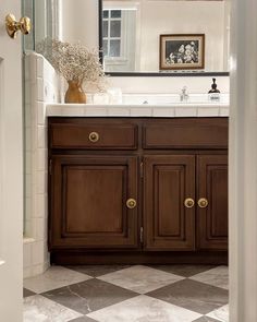 a bathroom with a checkered floor and wooden cabinets