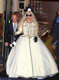 lady in white dress with black and white accessories walking down the street while wearing sunglasses