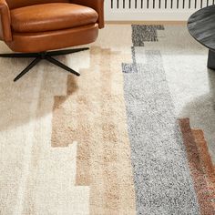 a brown chair sitting on top of a rug next to a wooden table and radiator