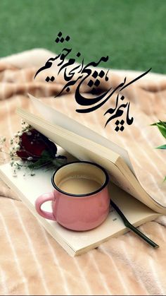 an open book with arabic writing and a cup of coffee sitting on top of it