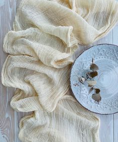 a white plate topped with two pieces of cloth next to an empty bowl on top of a wooden table