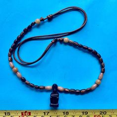 a wooden beaded necklace on a blue background next to a measuring tape and ruler