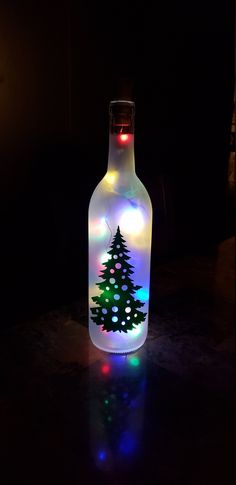 a lighted bottle with a christmas tree on it