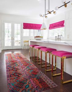 a kitchen with pink and gold stools next to an area rug on the floor