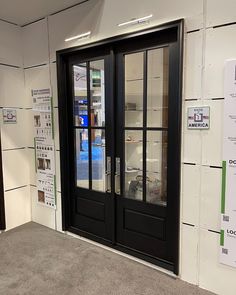 two black double doors in front of a white wall with signs on it and posters behind them