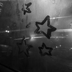 black and white photograph of rain drops falling on window glass with stars in the middle