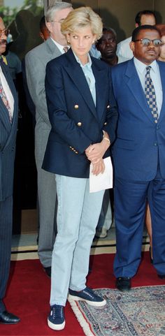 two men in suits and ties standing next to each other on a red carpeted area