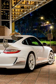 a white porsche sports car parked in front of a building at night with its doors open