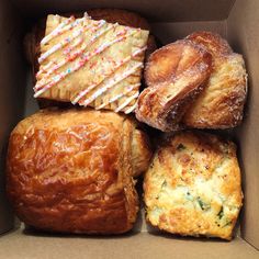 a box filled with lots of different types of breads and pastries on top of each other