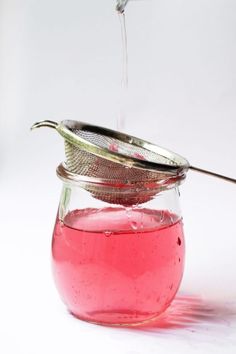 a glass jar filled with liquid and a strainer on the top is pouring water into it