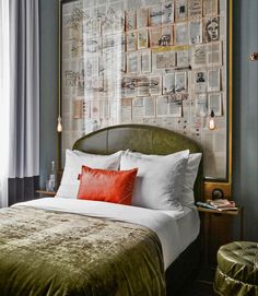 a hotel room with a bed, green velvet headboard and red pillows