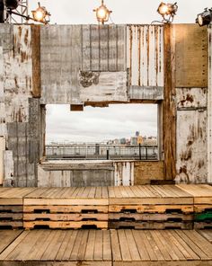 an empty stage with wooden pallets in the foreground and lights on either side