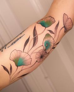 a woman's arm with flowers and leaves painted on the back of her arm