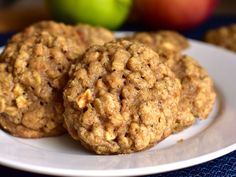 three oatmeal cookies on a plate with apples in the backgroud