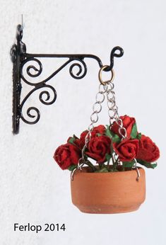 there is a potted plant hanging from a hook on the wall with flowers in it