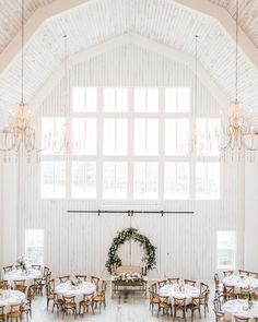 the inside of a large white building with tables and chandeliers hanging from the ceiling