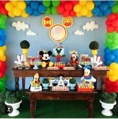 a mickey mouse themed birthday party with balloons and desserts on the table in front of it