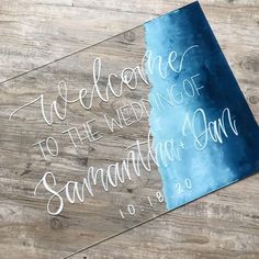 the welcome sign is placed on top of a wooden table with blue watercolor paint