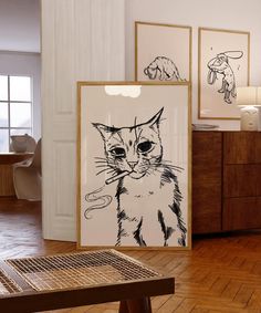 a cat is sitting on the floor next to some framed pictures