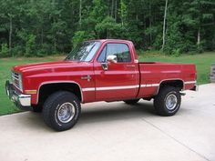 a red pick up truck parked on top of a driveway