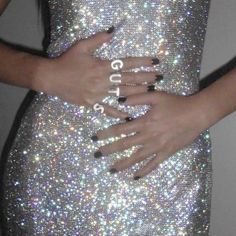 a woman in a silver dress with black and white nails holding her hand on her hip