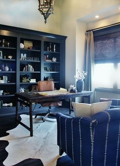 a living room filled with furniture and bookshelves next to a window covered in curtains