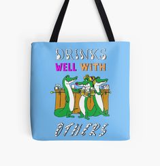 a blue tote bag with an image of two crocodiles drinking beer and the words drinks well with others