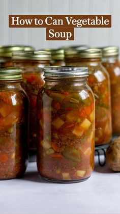 several jars filled with pickles and vegetables sitting on a table next to sliced carrots