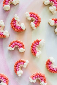 some pink and white decorated cookies are on a plate next to each other in the shape of letters