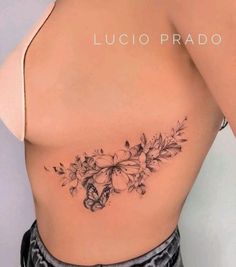 a woman's back with flowers and butterflies on her left side ribcage