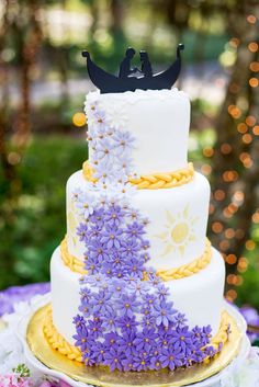 a three tiered cake with purple flowers on it