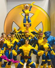 a group of action figures standing next to each other in front of a yellow and blue sign